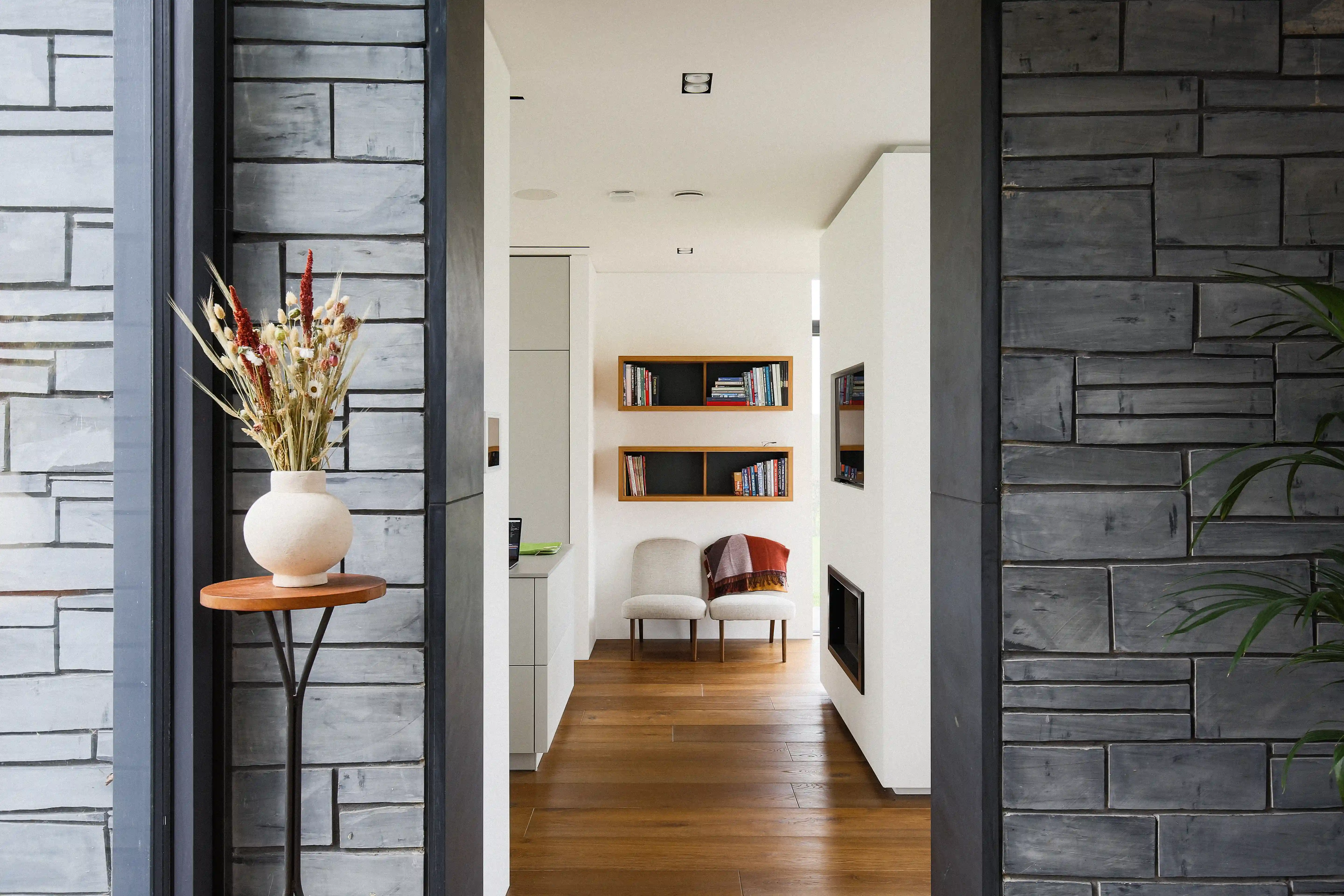 View from the stone-lined entrance through to the living room, with built-in shelving and a fireplace