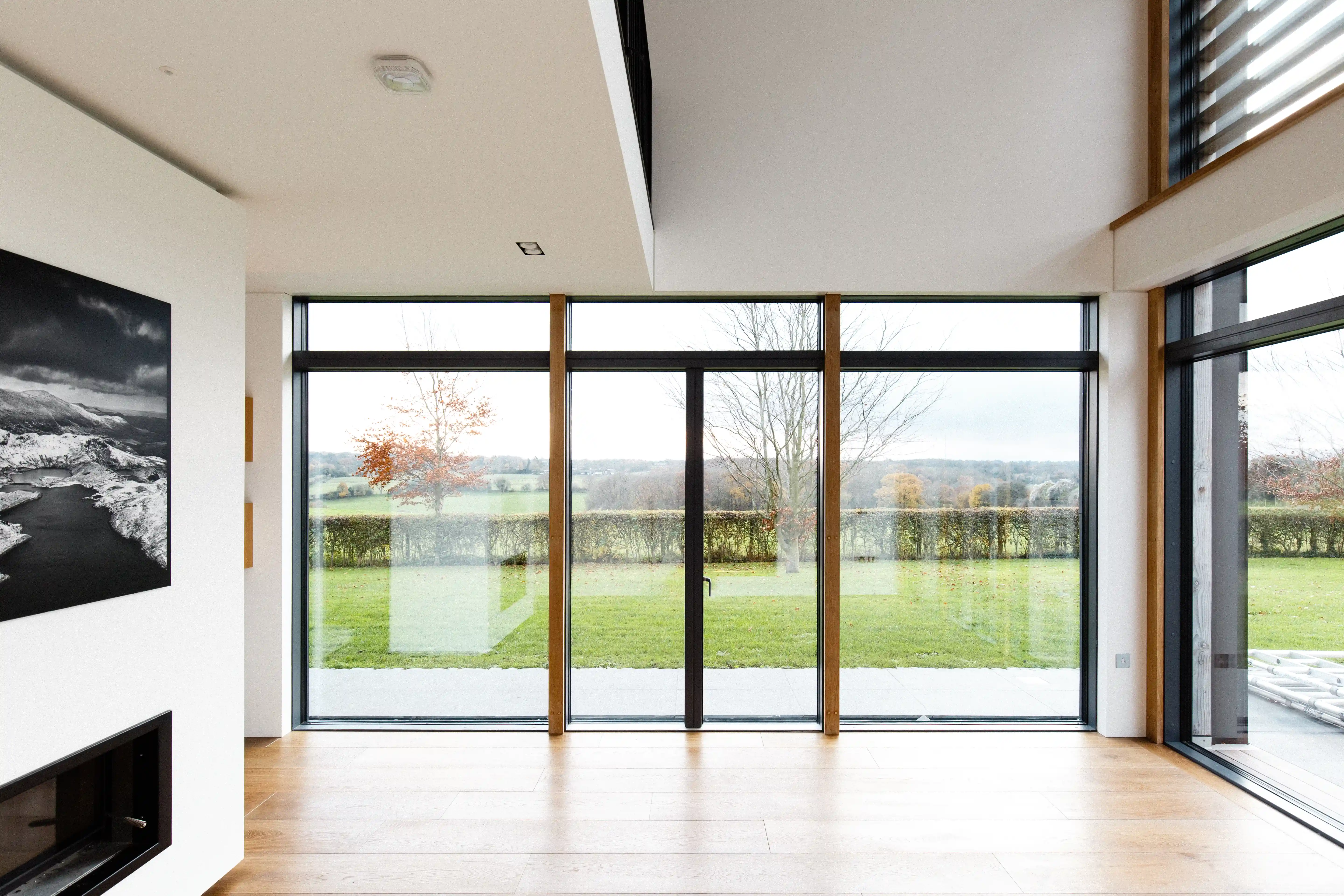 Living room with full-height glazing framing the view across the lawn to open countryside