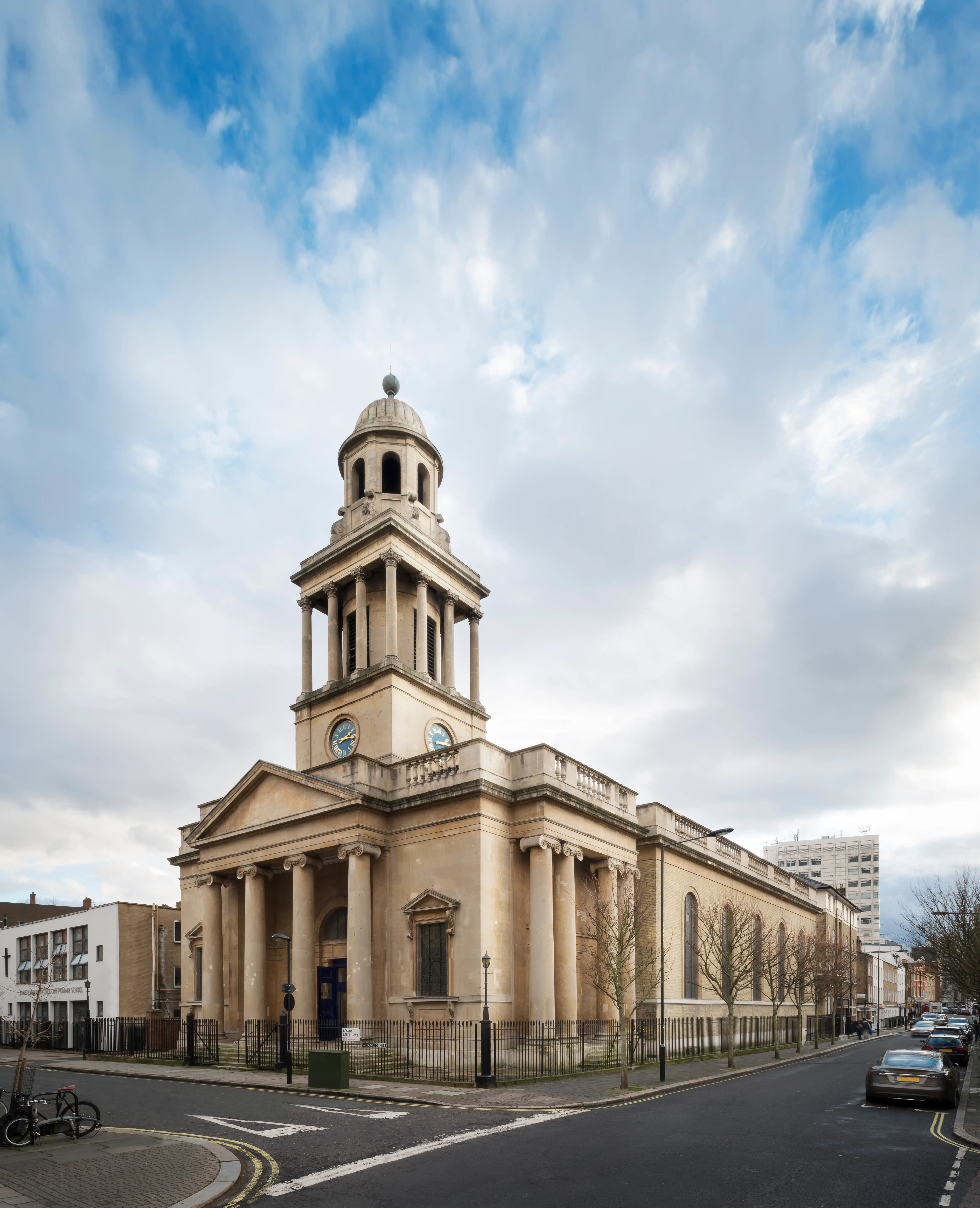 The restored church exterior, its Corinthian portico and tower seen from the street corner
