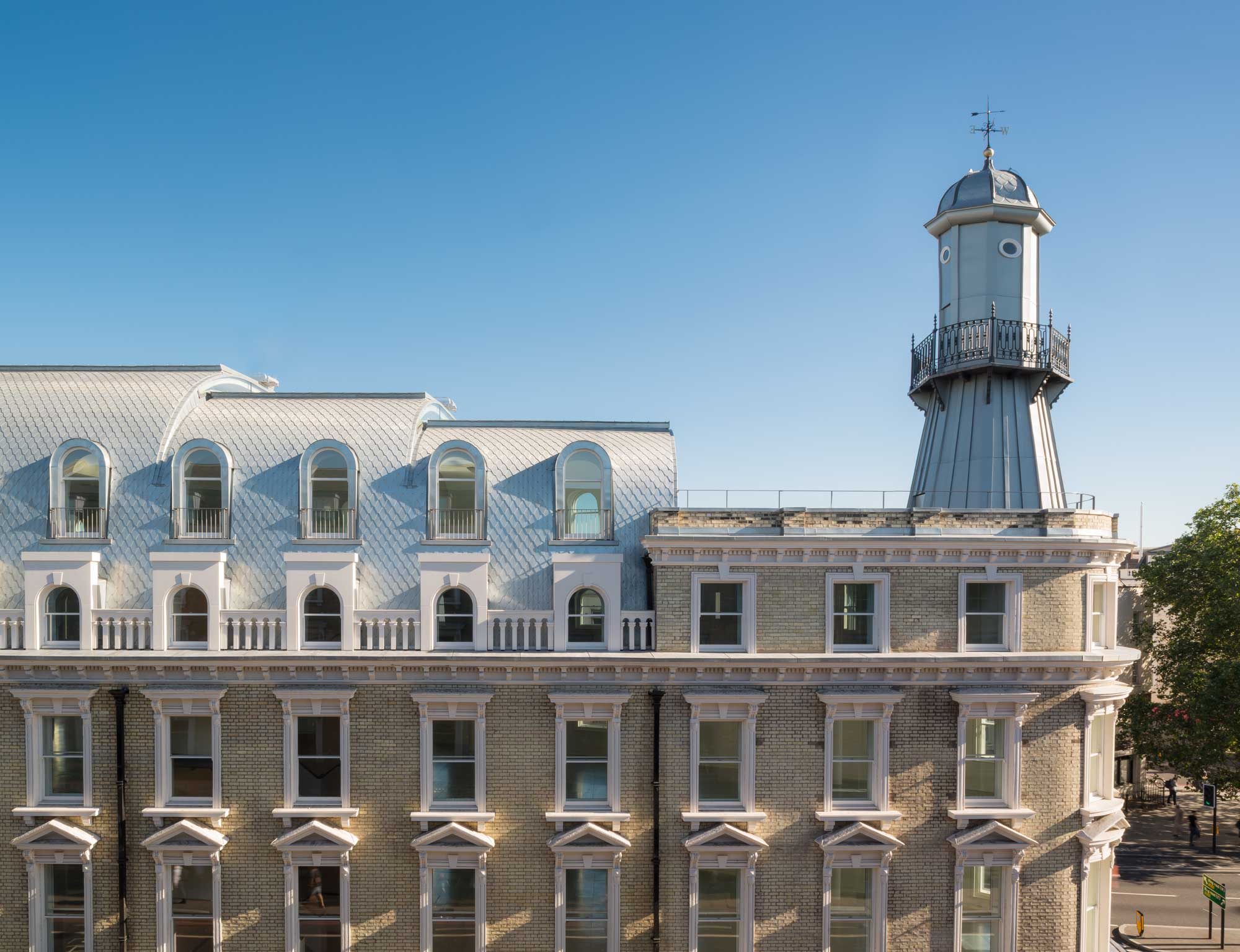 The lighthouse turret and the arched dormers of the new mansard roof seen across the rooftops in daylight
