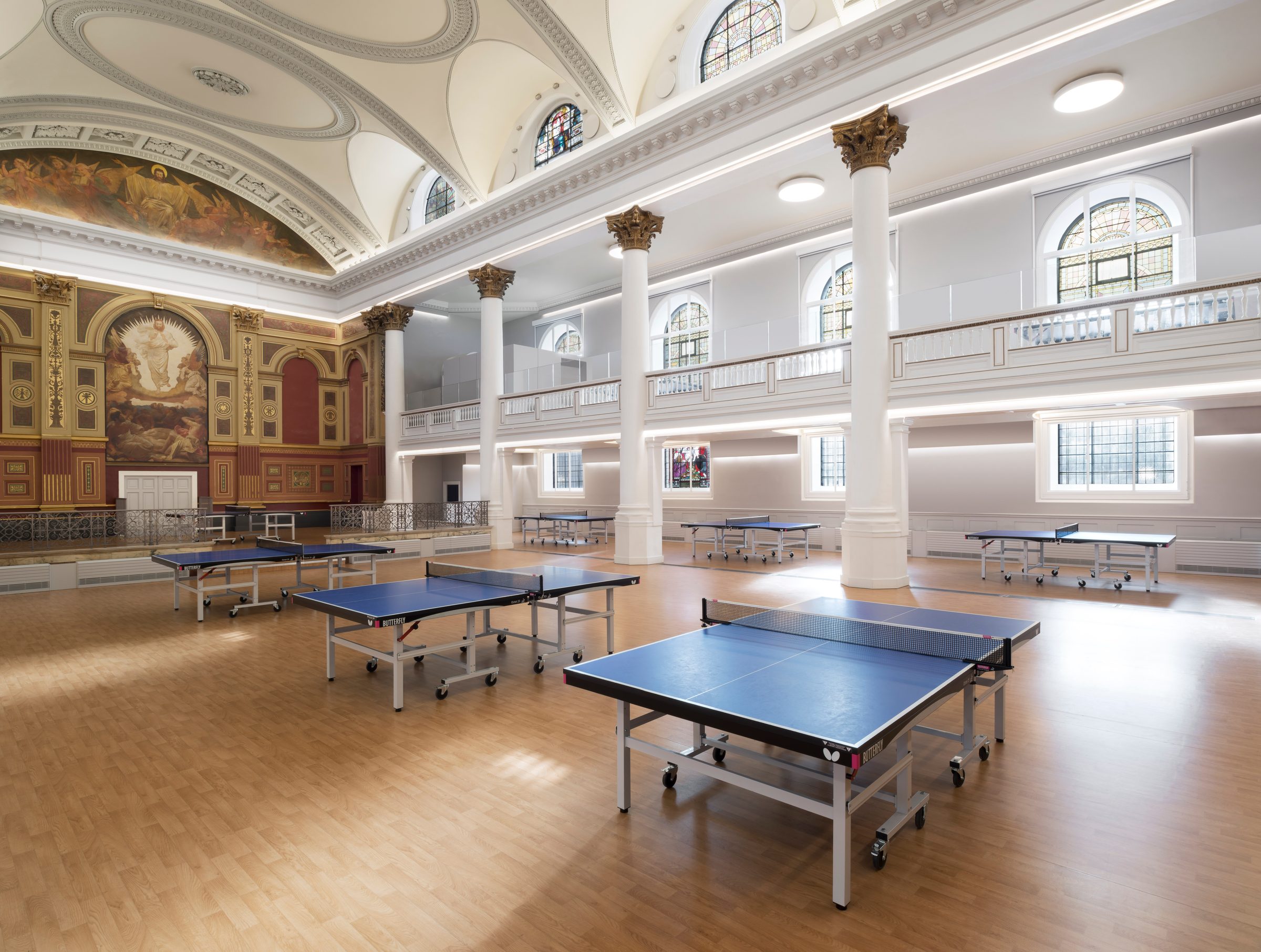 The main hall in use for table tennis, with the painted apse and colonnade beyond