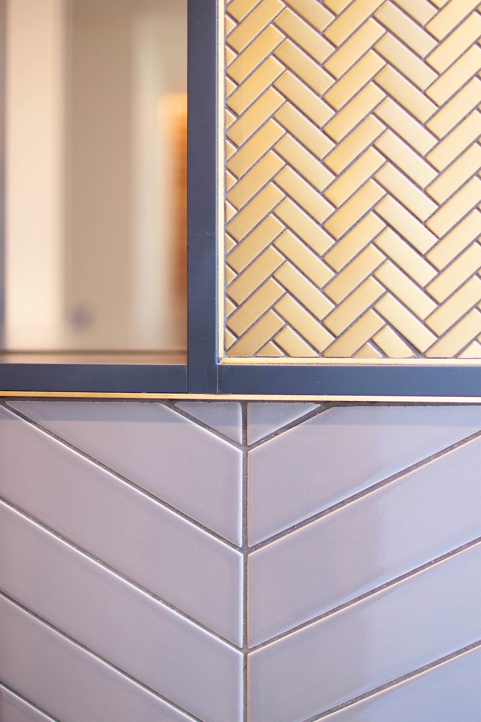 Tiling detail, herringbone above and chevron below, divided by a dark metal frame