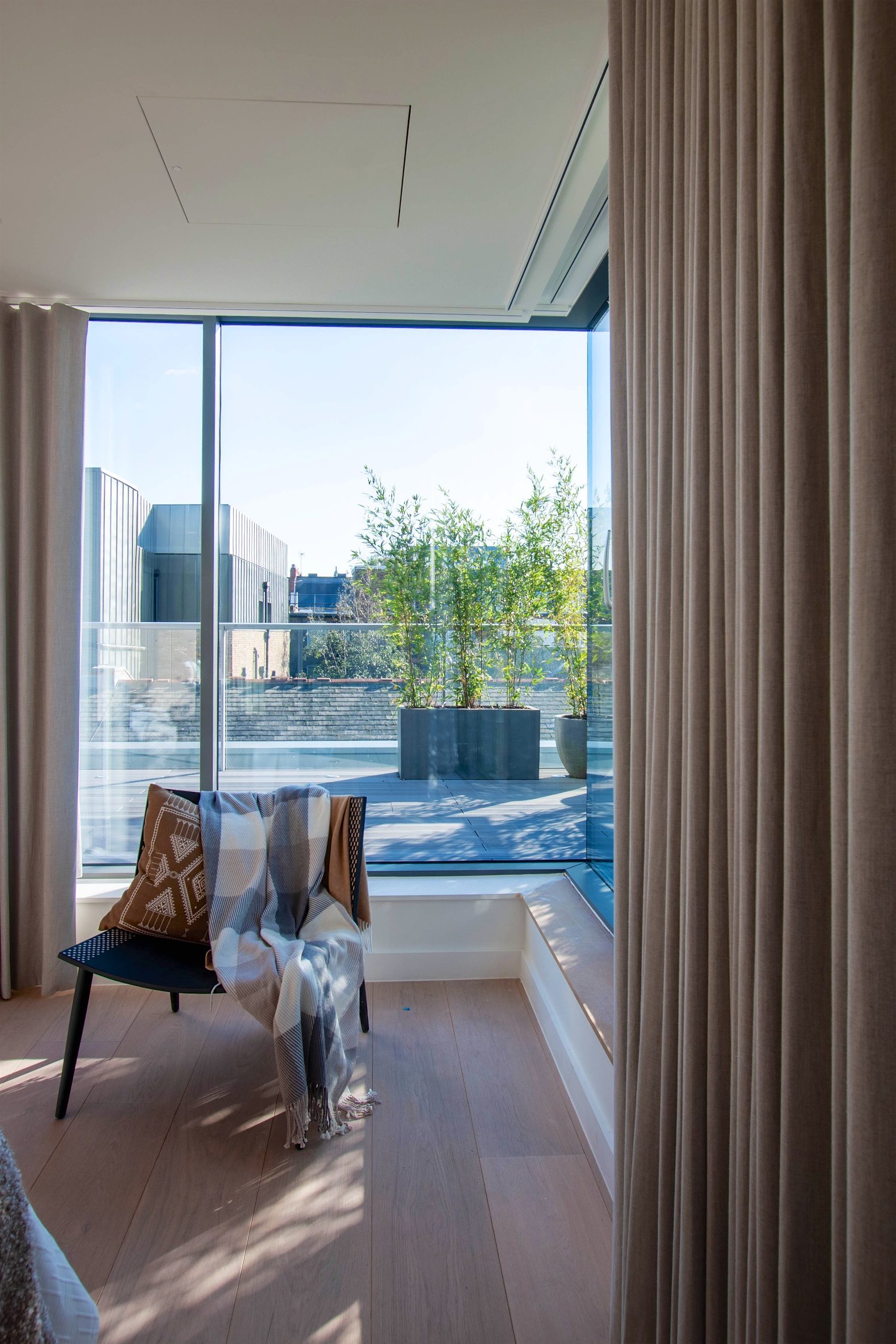 Corner glazing opening onto the terrace, with bamboo planters and full-length linen curtains