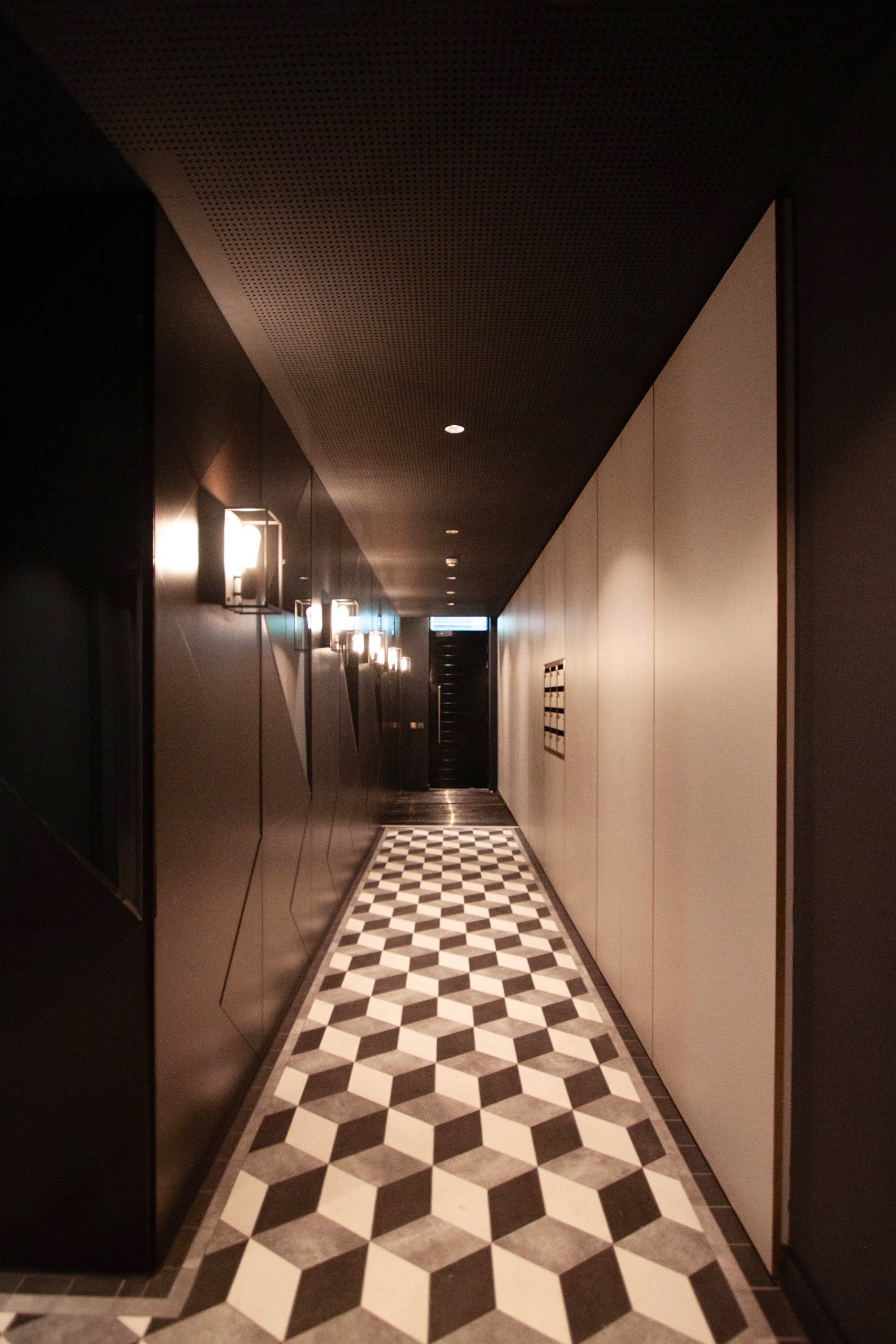 Communal entrance corridor with dark panelling, wall lights and a geometric tiled floor