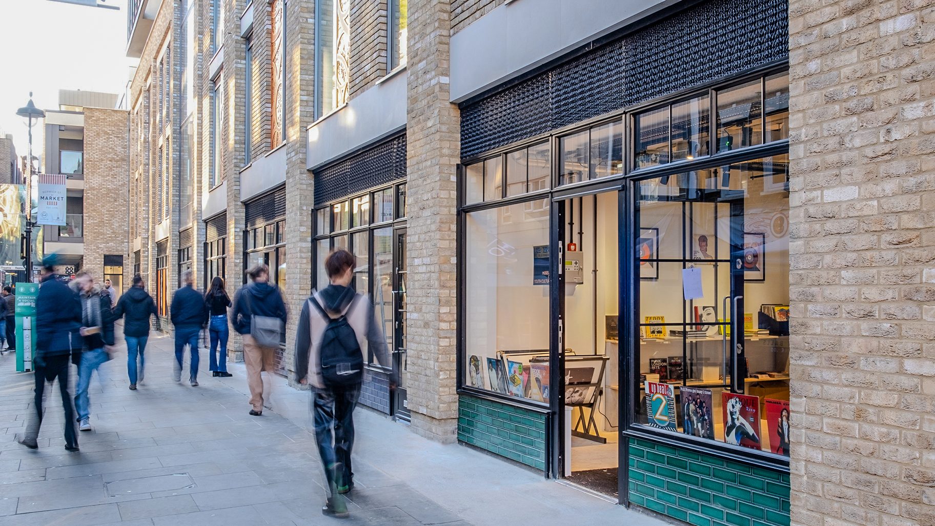The rebuilt shopfronts along the street, with black steel frames, green glazed tiling and yellow brick piers