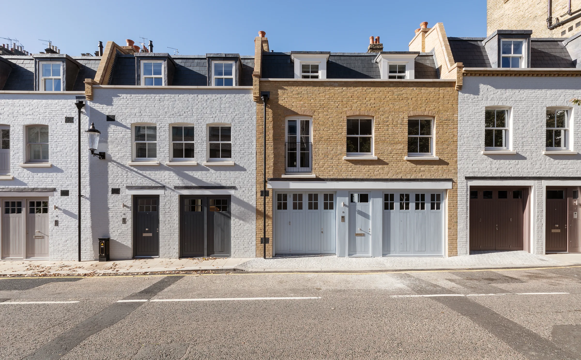 The mews frontage, with painted and stock brick houses, dormer windows and garage doors at street level